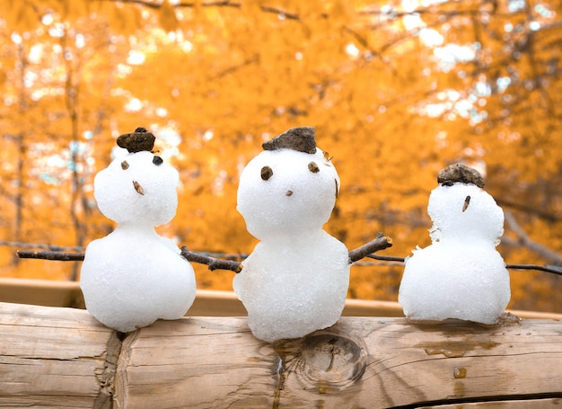 Drie kleine sneeuwmannen tegen de gouden herfst achtergrond