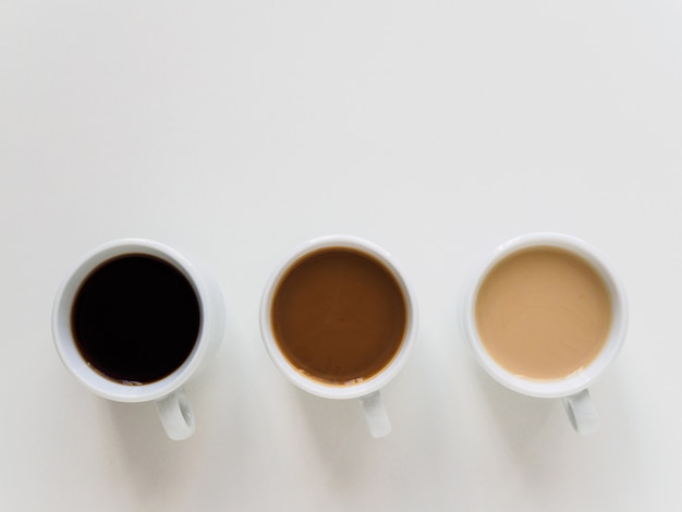 Drie kopjes verschillende koffie op een witte tafel