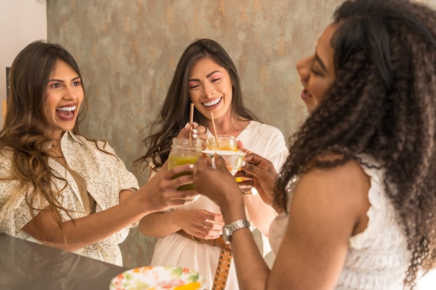 Drie Latijns-gelukkige vrouwen vieren met sappen in een cafetaria