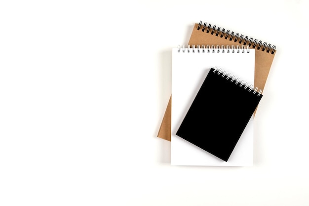 Foto drie lege notitieblokken op een spiraal gestapeld in een stapel op een witte achtergrond notebooks met wit, zwart en gerecyclede vellen onderwijskantoor
