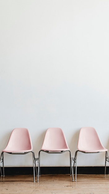 Drie lege pastelroze stoelen in een kamer