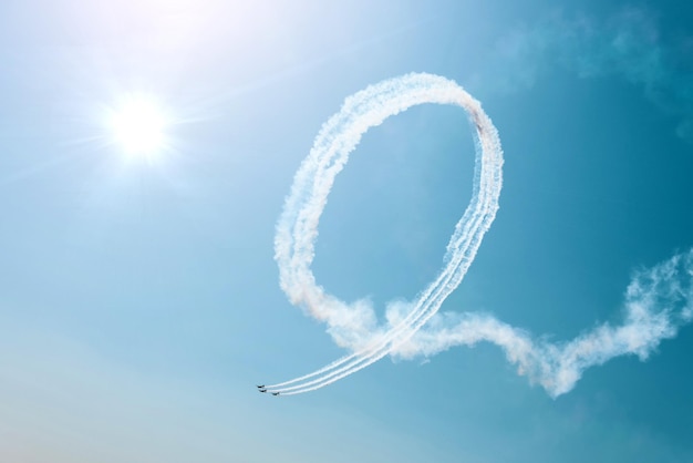 Drie lightengine-vliegtuigen voeren kunstvluchten uit De felle zon verlicht de vliegtuigen en de schaduwen vallen op de rook die ze in de lucht achterlaten