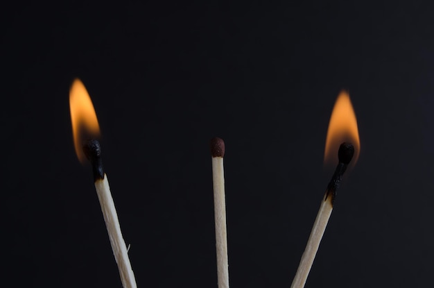 Drie lucifers op een zwarte achtergrond brandende lucifers