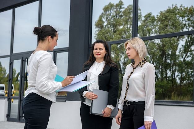 Drie managers met mappen poseren buiten kantoorgebouw