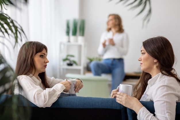 Drie meisjes bespreken nieuws en drinken thee in het appartement