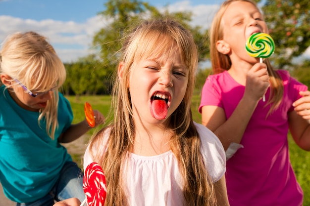 Foto drie meisjes die lollypops eten