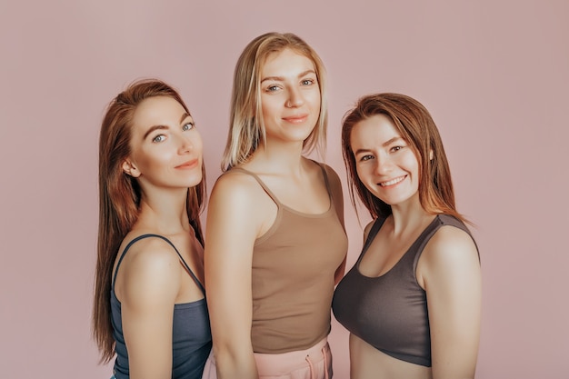 Drie meisjes in comfortabele huiskleren samen op een roze muur