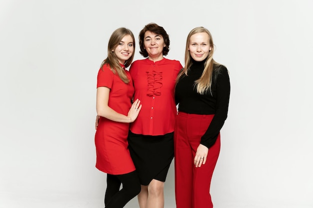 Drie meisjes staan op een witte achtergrond in de studio en kijken naar de camera. groepsportret. moeder met dochters op een witte achtergrond.