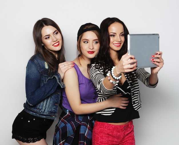 Drie meisjesvrienden die selfie met digitale tablet nemen, studioschot over grijze vackground