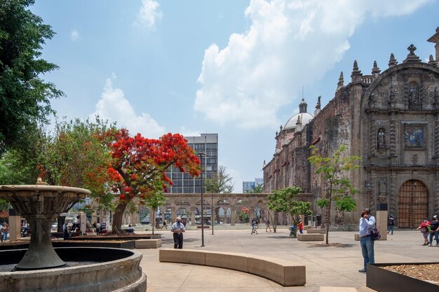 Drie mensen lopen kasteel of kerk, vuile vloer en bomen op de voorgrond De stenen kerk met dak van kleipannen