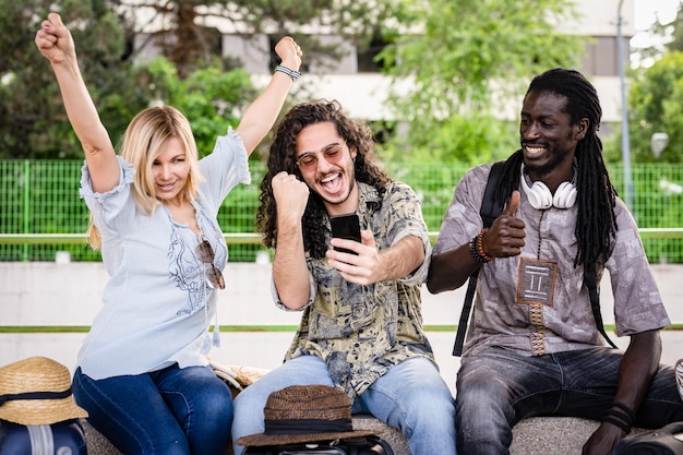 Foto drie mensen uit verschillende etnische groepen en culturen die met de trein reizen, gelukkige vrienden die smartphone en technologie gebruiken om de wereld rond te reizen
