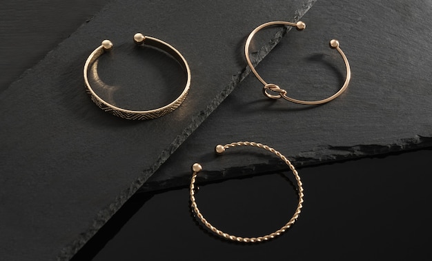 Drie moderne design gouden armbanden op zwarte stenen platen op zwarte achtergrond