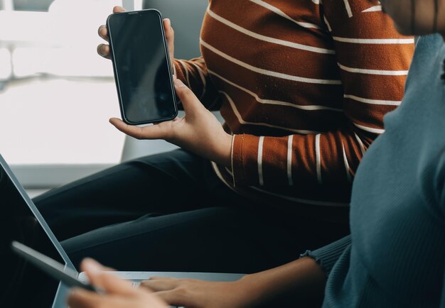 Drie mooie Aziatische meisjes met behulp van smartphone en laptop chatten samen op de bank in een café met kopieerruimte moderne levensstijl met gadgettechnologie of werkende vrouw op casual business concept