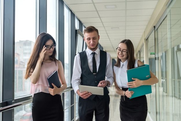 Drie mooie zakenpartners die administratie in moderne bureaugang bespreken. Bijeenkomst concept