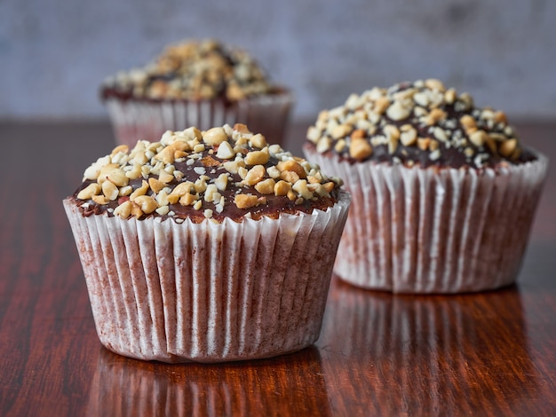 Drie muffins met pinda's en chocolade glazuur in lijn. Selectieve aandacht. Detailopname.