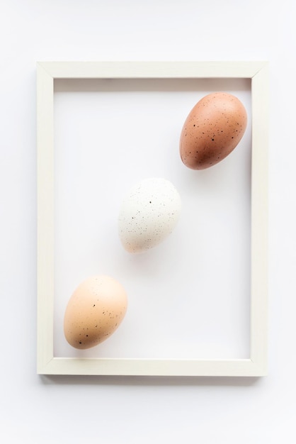 Foto drie natuurlijke eco-eieren op een witte achtergrond met kopie ruimte voor tekst in een frame geometrie minimaal concept weergave van bovenaf paaskaart zachte selectieve focus