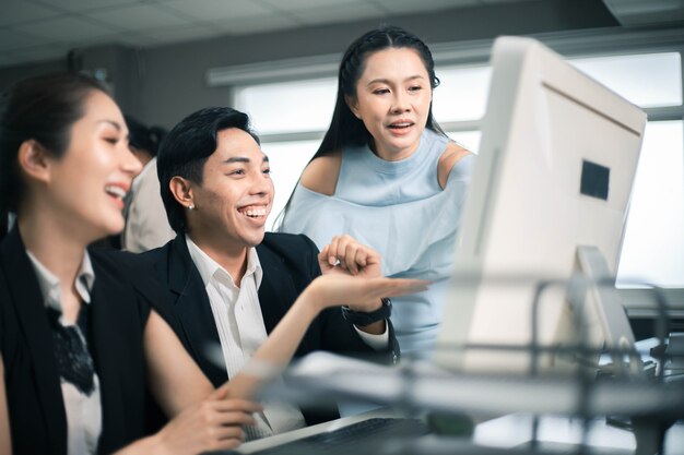 Drie opgewonden medewerkers lezen goed nieuws online in een computerdesktop op kantoor