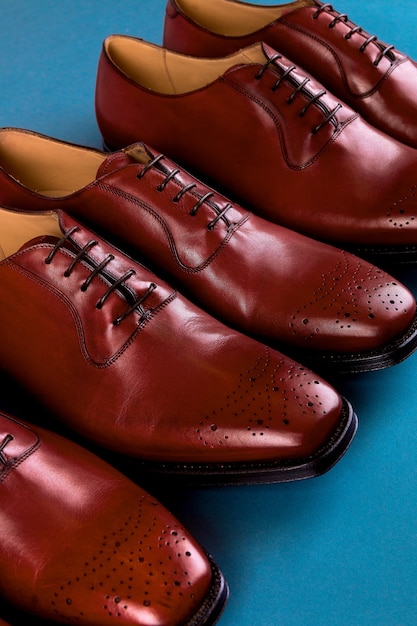 Drie paar brogues in een cirkel, bruine oxford schoenen op blauwe achtergrond, bovenaanzicht, kopie ruimte.