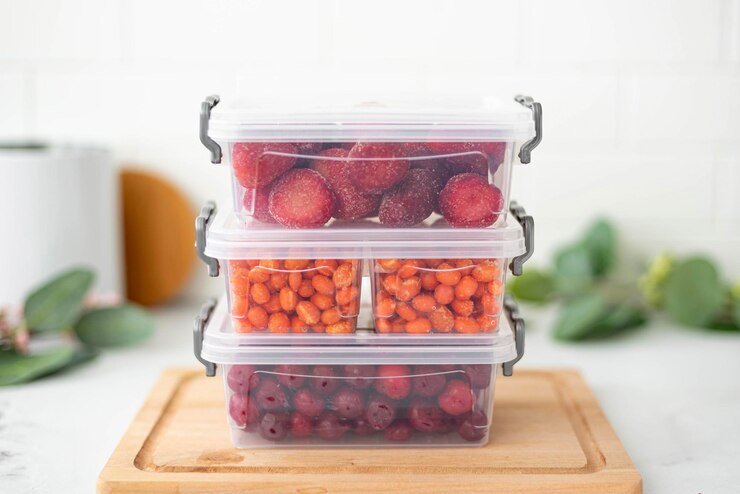 Drie plastic containers met bevroren bessen op de keukentafel close-up