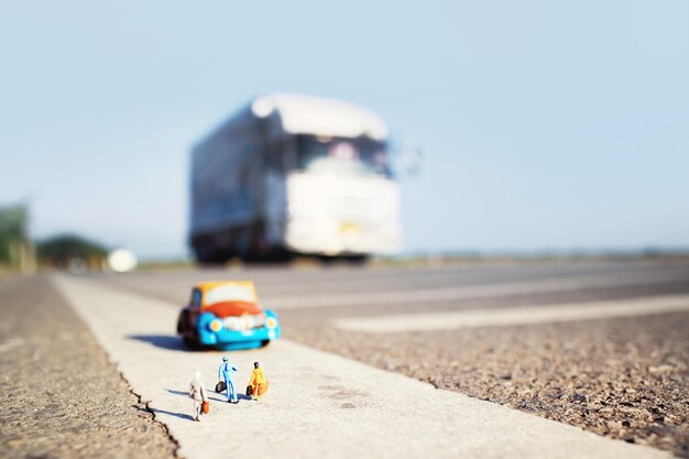 Drie reizigersminiatuur en een taxi op de achtergrond van de landweg Ondiepe scherptediepte en vintage kleur