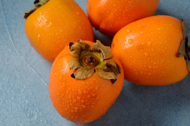 Foto drie rijpe dadelpruimen op een blauwe achtergrond. heerlijk vers kakifruit