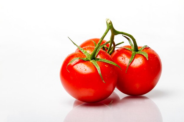 Drie rijpe verse tomaten aan de tros met dauw erop