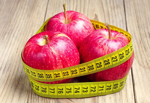 Drie rode appels met meetlint op houten tafel