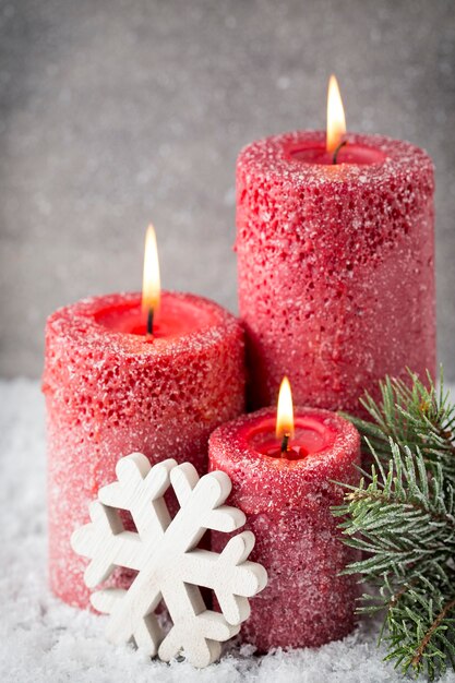 Drie rode kaarsen op grijze ondergrond, kerstversiering. Adventstemming.