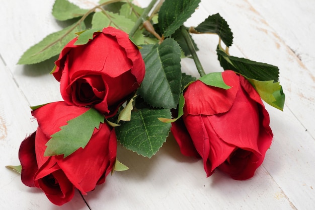 Drie rode rozen op de houten tafel