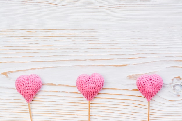 Drie roze gebreide harten op een witte houten achtergrond