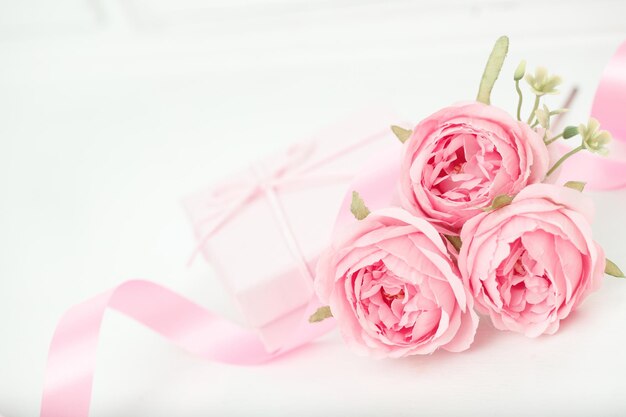 Drie roze rozen met lint en geschenkdoos op de witte tafel