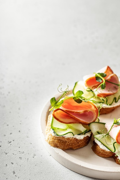 Drie sandwiches stokbrood vlees roomkaas microgreenery komkommer op witte achtergrond tekst space