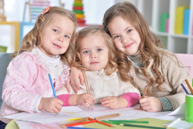 Drie schattige kleine meisjes tekenen met potloden