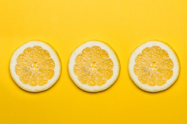 Drie schijfjes citroen op een gele achtergrond