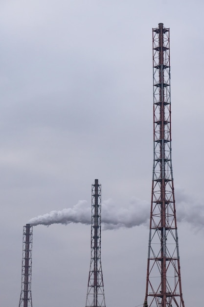 Drie schoorstenen van een elektriciteitscentrale die dikke rook produceren