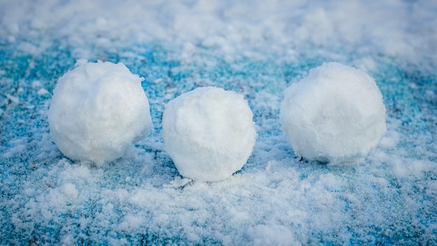 Drie sneeuwballen op een besneeuwd blauw tafeloppervlak