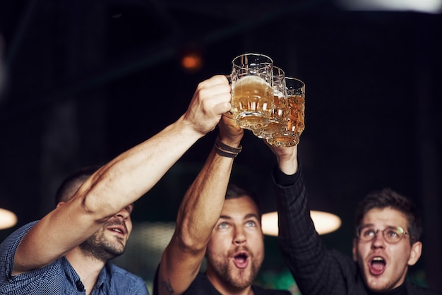 Foto drie sportfans in een bar voetbal kijken