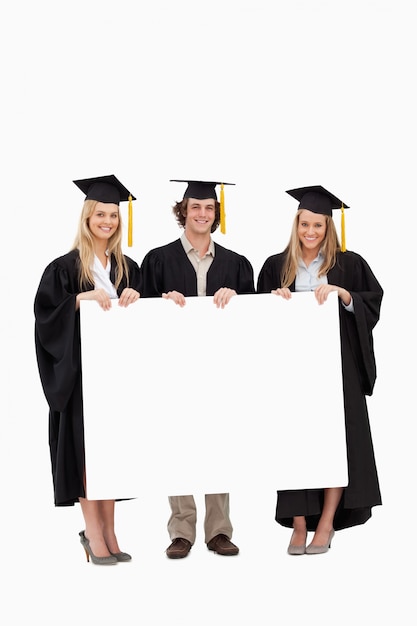 Drie studenten in gediplomeerde mantel met een leeg bord