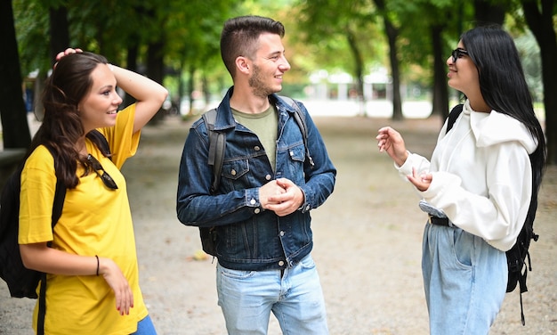 Drie studenten praten met elkaar buiten op de binnenplaats van een universiteit