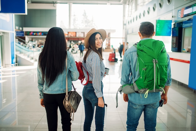 Drie toeristen met bagage die in luchthaven wachten