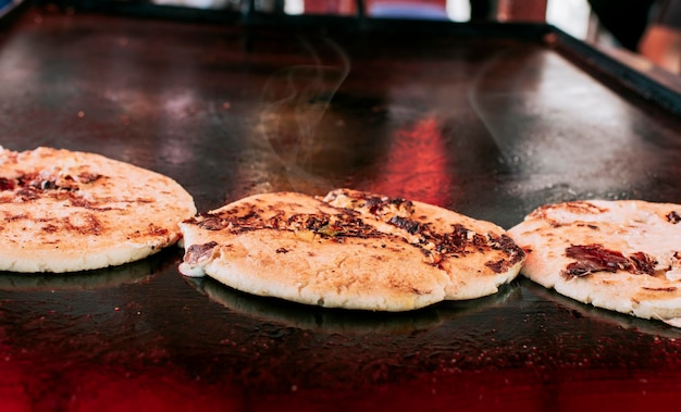 Drie traditionele Nicaraguaanse pupusas met gesmolten gegrilde kaas Traditionele kaas pupusas op de grill Close-up van traditionele handgemaakte pupusas op de grill