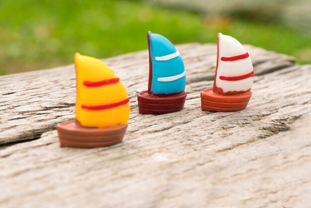 Foto drie veelkleurige speelgoed zeilboot op een oud houten oppervlak met scheuren