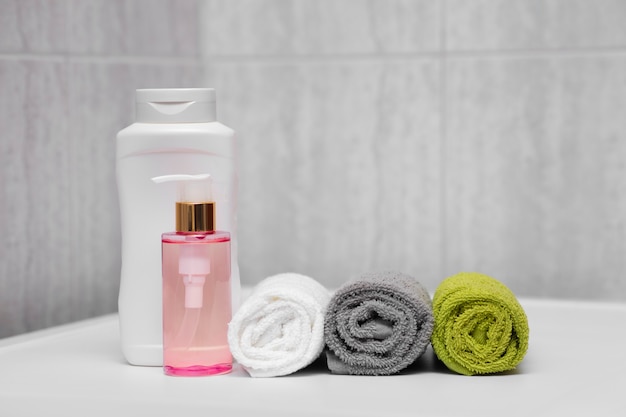 Drie verschillende kleuren handdoeken, shampoo en verzachtende olie, after shower lotion