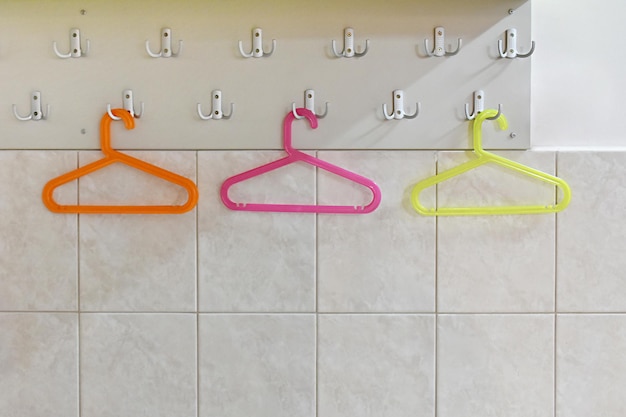 Foto drie verschillende kleuren hangers aan de haken aan de muur