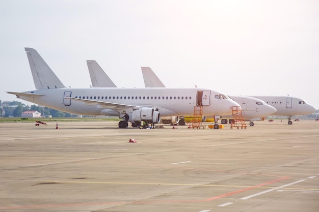 Drie verschillende narrowbody-vliegtuigen die op de luchthaven geparkeerd staan, staan in een rij