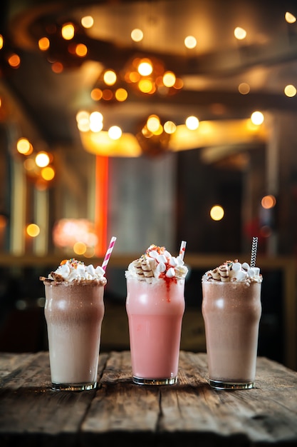 Drie verschillende zoete milkshakes op houten tafel