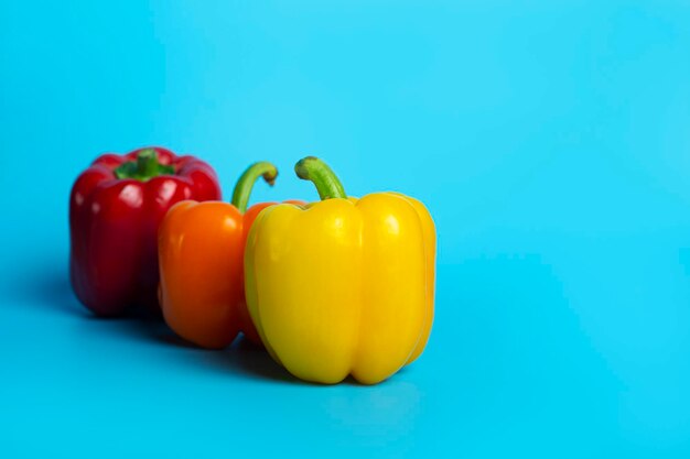 Drie verse heldere paprika's op een blauwe achtergrond bovenaanzicht plat lag