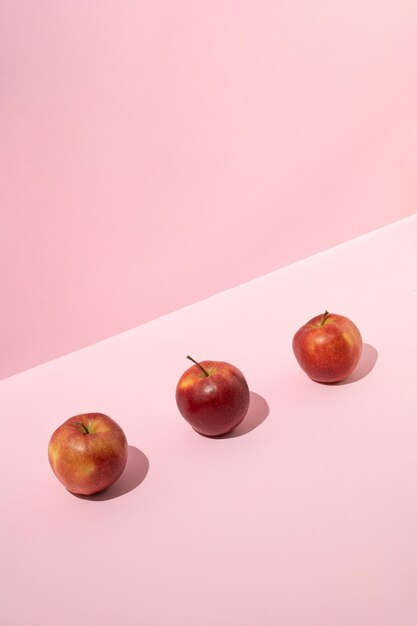 Foto drie verse rode appels op roze achtergrond minimaal fruitconcept