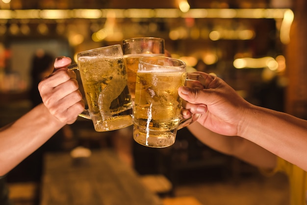 Drie vrienden die met glazen licht bier in de bar roosteren