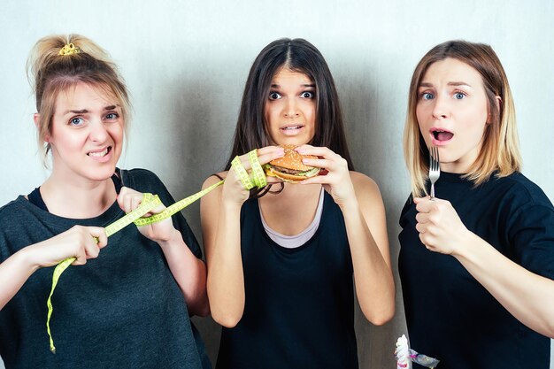 Drie vrienden overtuigen het meisje om geen hamburger te eten concept van dieet en vrouwelijke vriendschap